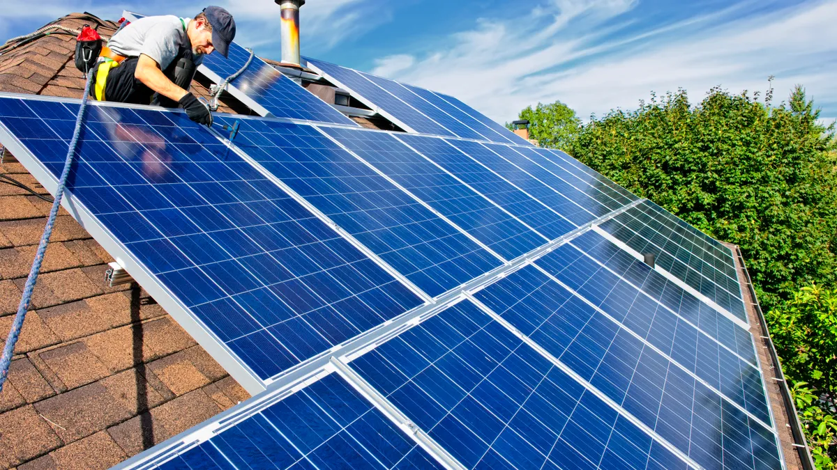 Man installing alternative energy photovoltaic solar panels on roof