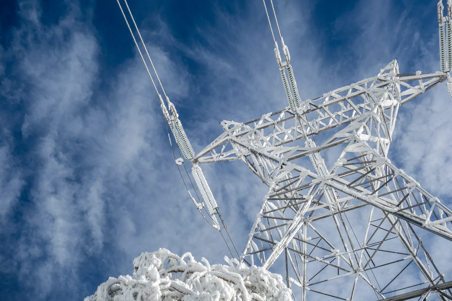 High voltage electric tower on a snowy day in the mountains.