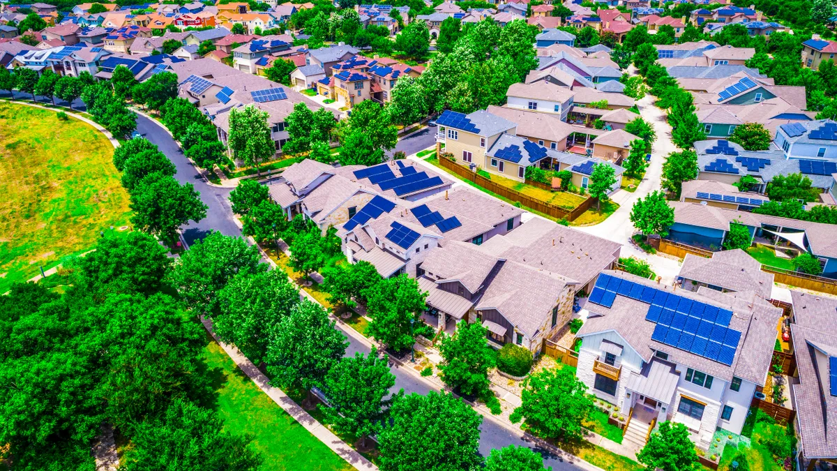 Solar panels on rooftops in a leafy, suburban neighborhood.