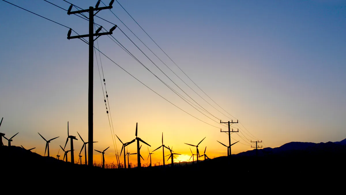 Windmill farm in the desert at sunset in Palm Springs, California with power lines going to the city.