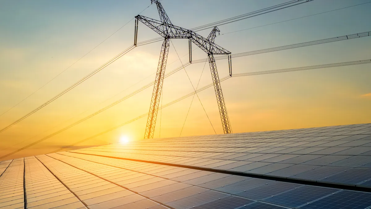 High voltage pylons with electric power lines transfering electricity from solar photovoltaic cells at sunrise.