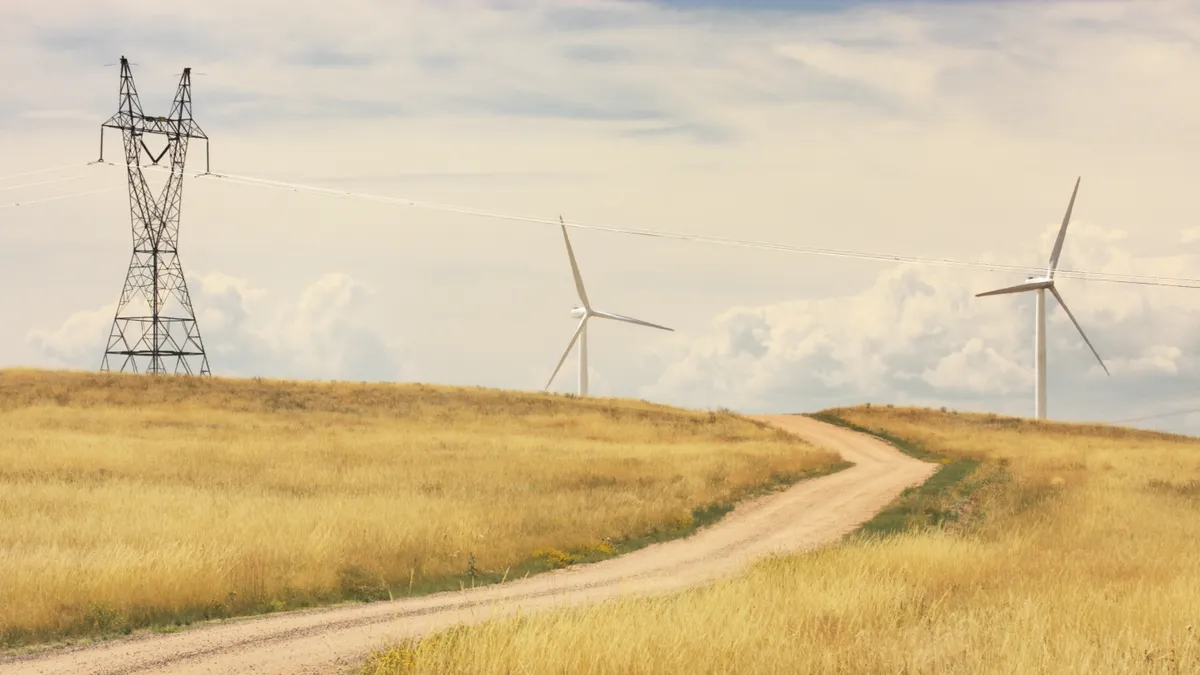 Rural lane meanders among modern windmill technology and steel electrical pylons. Laramie, Wyoming, 2009