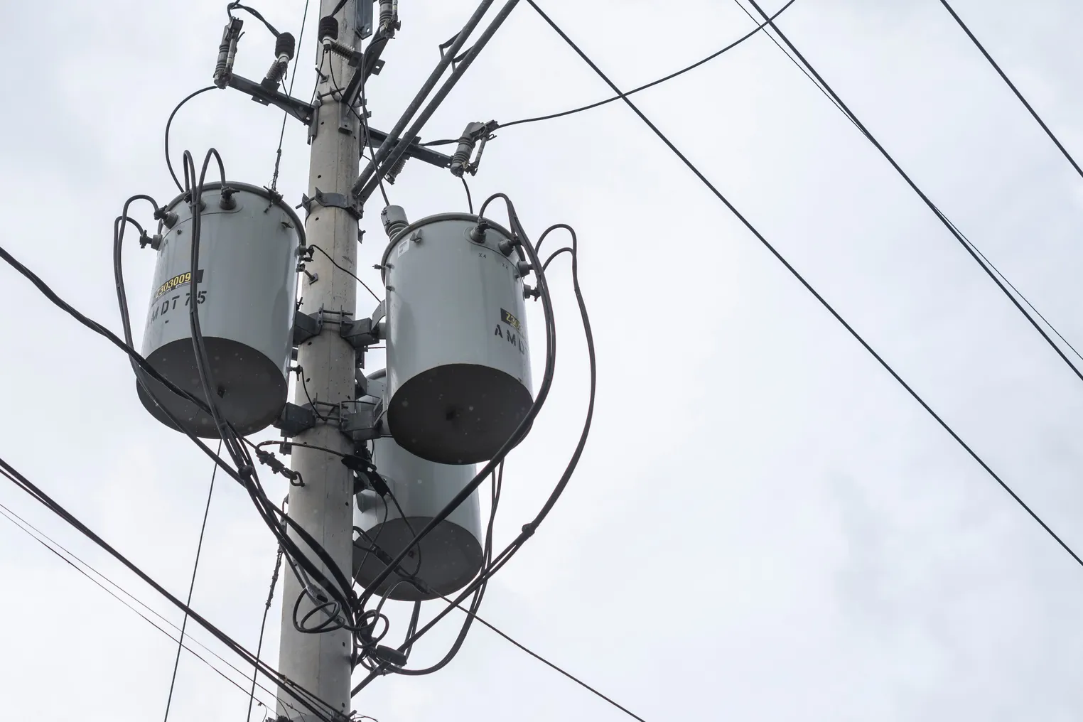 Three single-phase pole-mounted distribution transformers. During an overcast sky or before a storm.